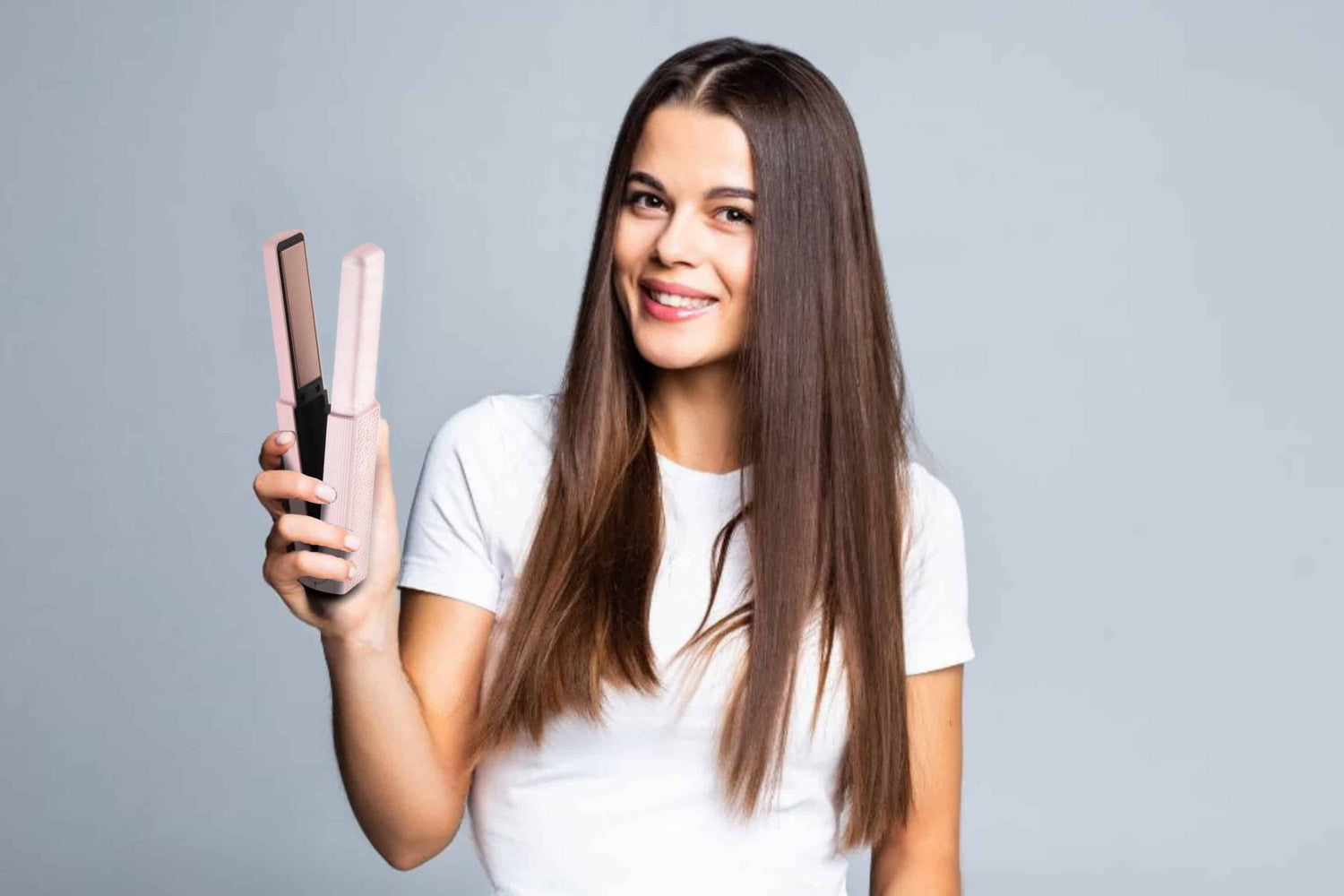 Image of woman with beautiful straight brunette hair holding and showcasing cordless Hair Straightener On-The-Go Sakura Pink color in her hand